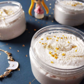 A few jars of white sugar scrub with gold glitter and stars on the top.