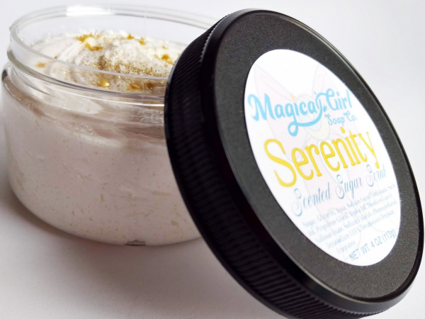A small jar of white sugar scrub with gold glitter and stars on the top.