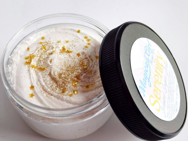 A small jar of white sugar scrub with gold glitter and stars on the top.