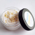 A small jar of white sugar scrub with gold glitter and stars on the top.