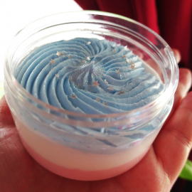 A photo of a jar of whipped soap. The soap is red, white, and blue with glitter.